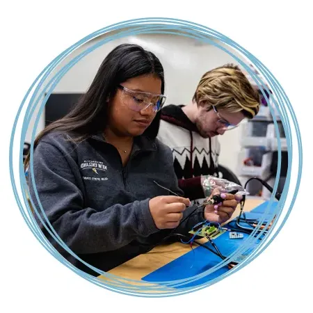 Two students soldering in the Makerspace