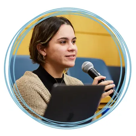 A student holds a microphone while they ask a question at a U N E lecture event